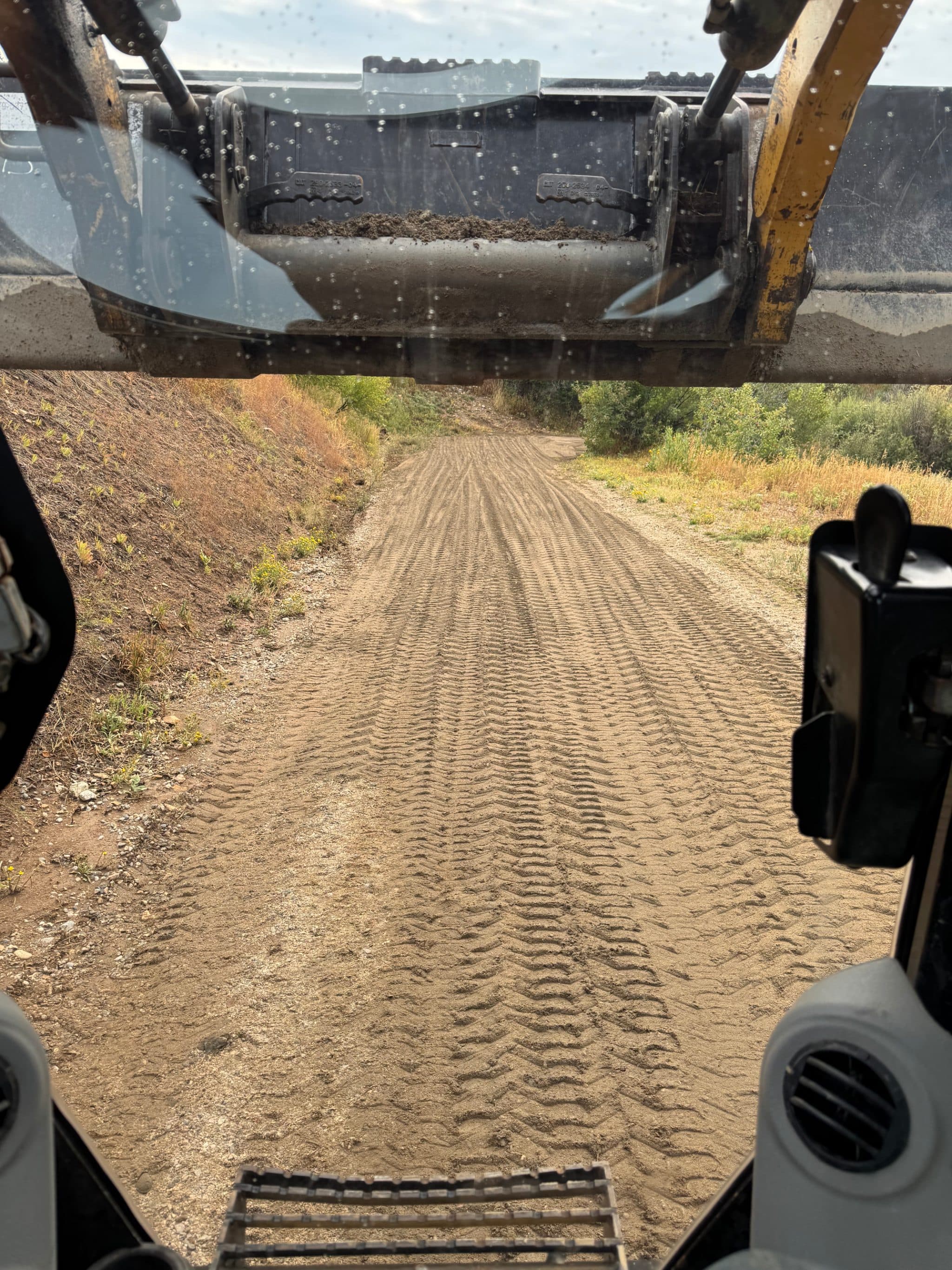 Tyre tracks pressed into a spread-aggregate haul road running ahead across a Steamboat-area site.